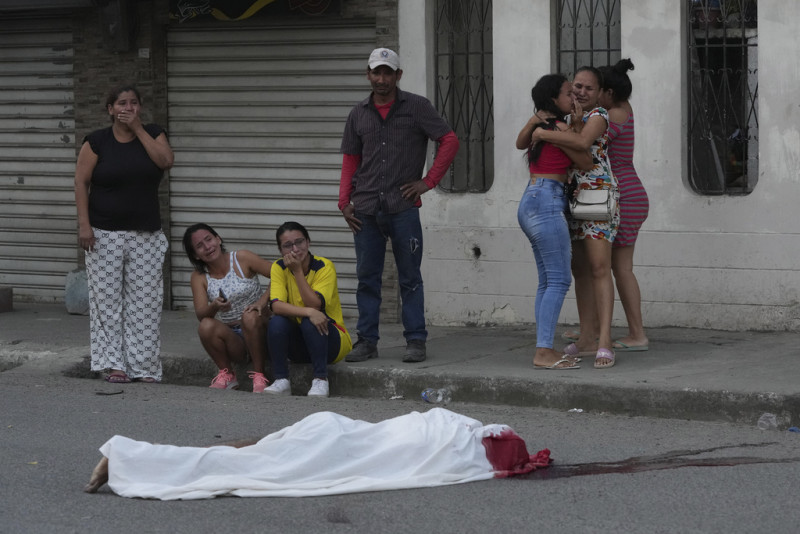 Varias personas lloran junto al cadáver de un hombre, asesinado en circunstancias desconocidas, en una calle de Durán, Ecuador, el 21 de julio de 2023
