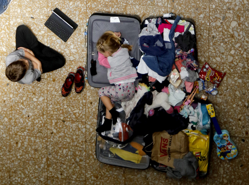 Esta niña busca refugio dentro de una maleta, símbolo inesperado de la incertidumbre que rodea a una familia argentina varada en el aeropuerto internacional José María Córdova de Rionegro, Antioquia.