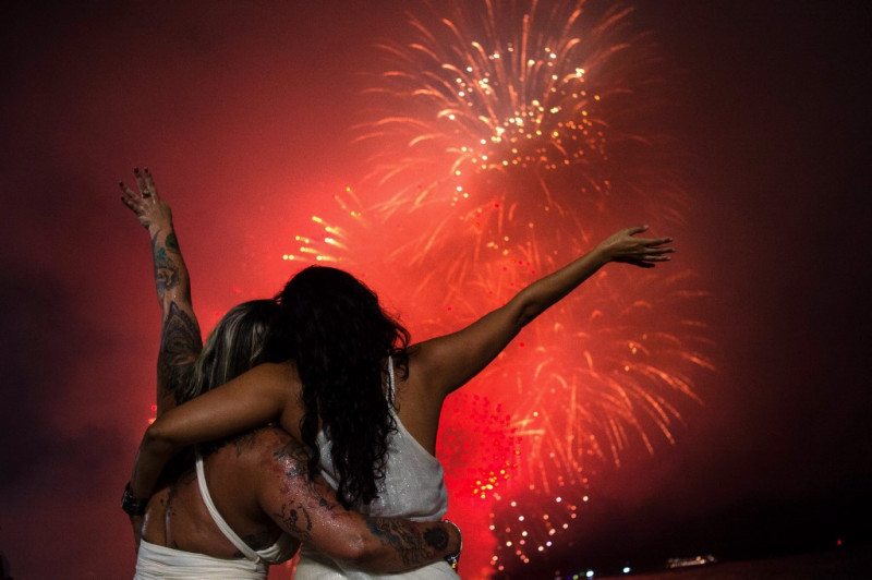 La gente celebra mientras ve los tradicionales fuegos artificiales de Año Nuevo desde el agua en la playa de Copacabana en Río de Janeiro, Brasil, el 1 de enero de 2024
