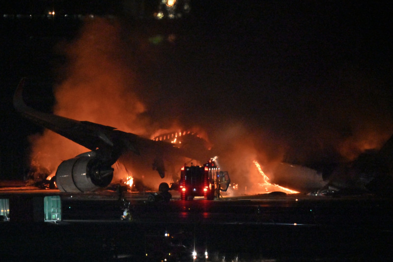 A Japan Airlines (JAL) passenger plane is seen on fire on the tarmac at Tokyo International Airport at Haneda on January 2, 2024. A Japan Airlines plane burst into flames on the runway of Tokyo's Haneda Airport on January 2 after apparently colliding with a coast guard aircraft, media reports said. (Photo by Richard A. BROOKS / AFP)