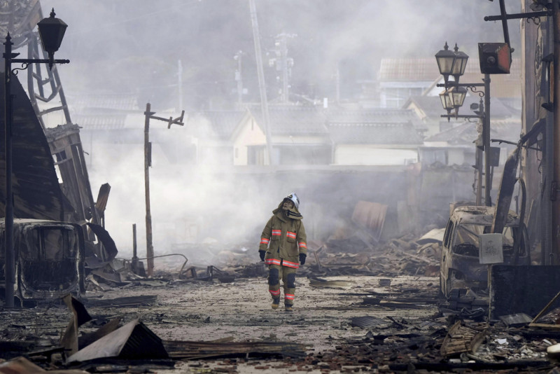 Un bombero camina entre los escombros y los restos de un incendio en un mercado, luego de un terremoto