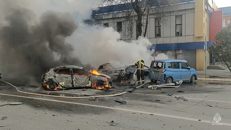 En esta fotografía tomada de un video difundido por el canal de Telegram del Ministerio de Situaciones de Emergencia de Rusia el sábado 30 de diciembre de 2023, se ve a bomberos que extinguen vehículos en llamas después de un ataque en Belgorod, Rusia.