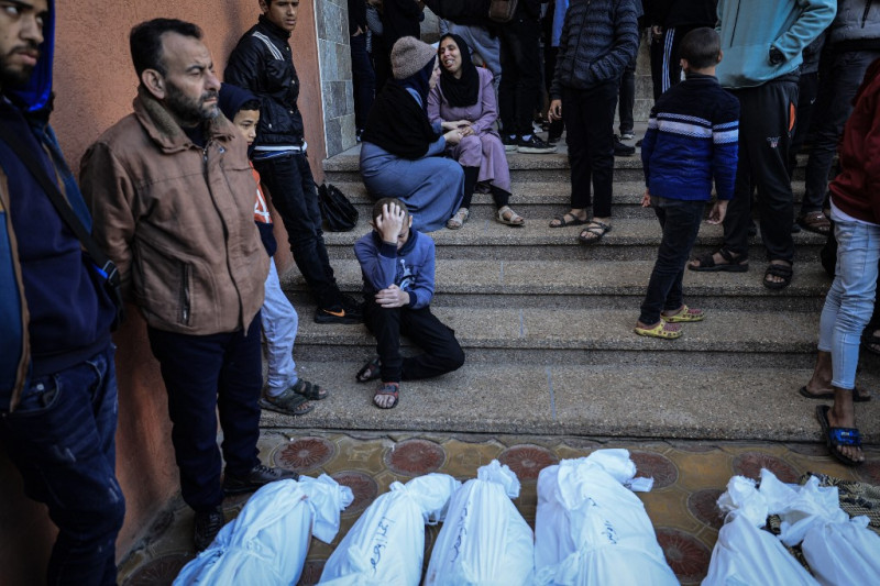 Varias personas se reúnen en torno a cadáveres de familias que murieron cuando la tienda en la que se refugiaban fue alcanzada por un bombardeo israelí