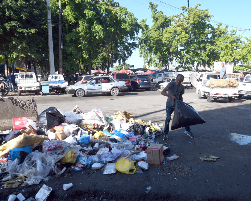 Un hombre arroja una bolsa de basura en un vertedero improvisado situado en la calle Libertad. Detras se encuentra el Mercado Nuevo de la Duarte.