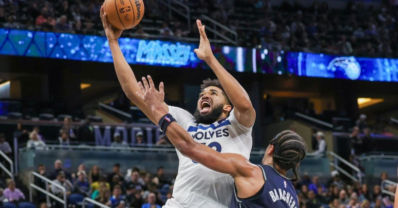 Karl-Anthony Towns de los Timberwolves realiza un intento al canasto sobre Paolo Banchero del Magic en partido del baloncesto de la NBA.