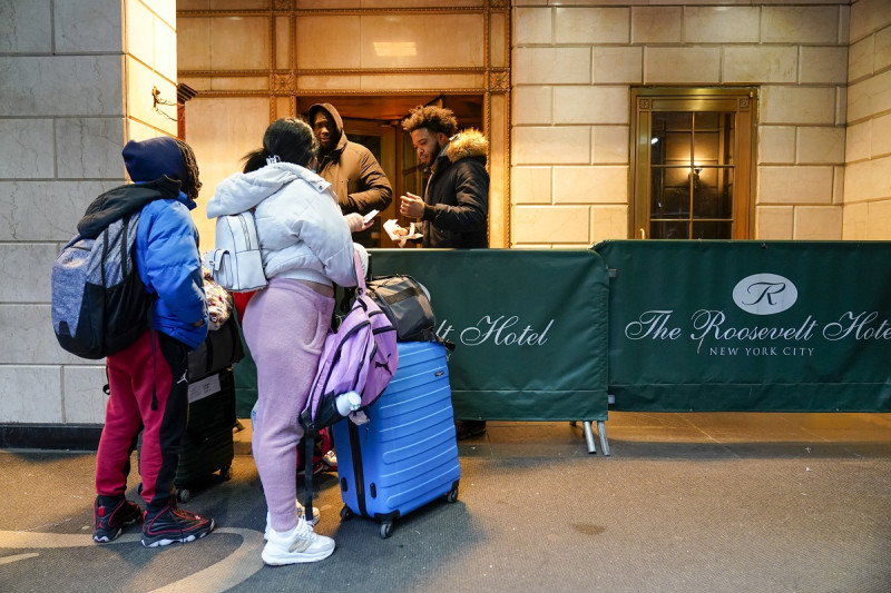 Una familia de migrantes muestra su documentación a los guardias de seguridad en el Hotel Roosevelt, el martes 9 de enero de 2024, en la ciudad de Nueva York.