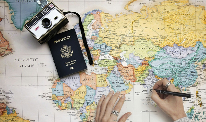 Fotografía ilustrativa de mapa del mundo con cámara y pasaporte.