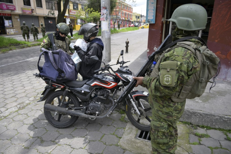 Miembros del Ejército inspeccionan a un hombre en bicicleta en el sur de Quito, el 13 de enero de 2024, mientras Ecuador se encuentra en "estado de excepción" desde la fuga de prisión de uno de los jefes narcos más poderosos del país