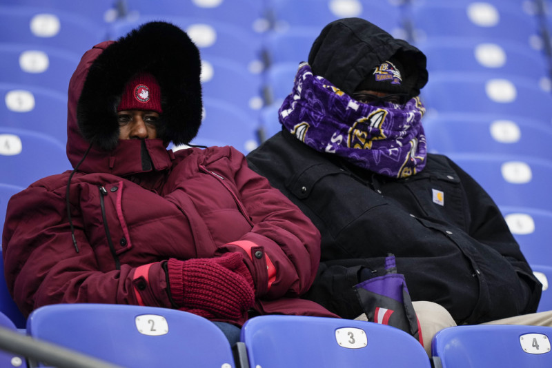 Dos personas de cobijan del frío en el partido de fútbol americano entre los Ravens de Baltimore y los Texans de Houston, en Baltimore, el 20 de enero de 2024.