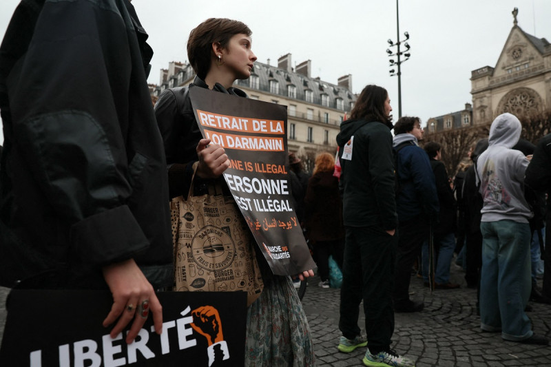 Un manifestante sostiene un cartel durante una manifestación contra la nueva ley de inmigración de Francia frente a la Iglesia de Saint-Germain l'Auxerrois en París el 25 de enero de 2024.