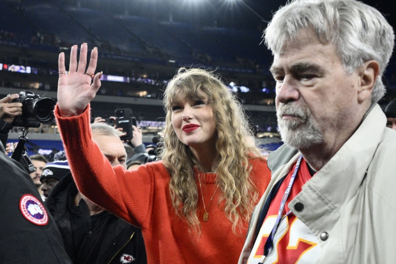 Taylor Swift saluda mientras camina con Ed Kelce