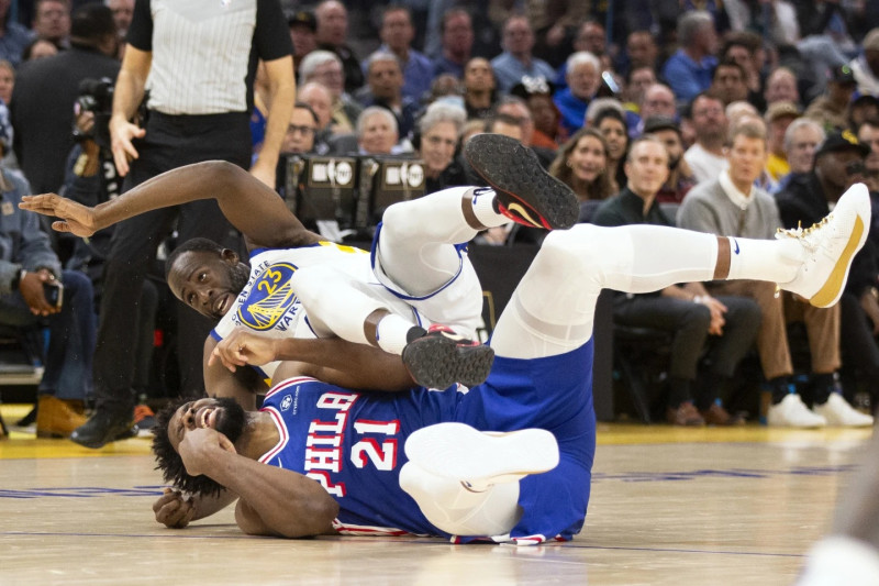 Draymond Green, de los Warriors, cae sobre Joel Embiid, de los Sixers, que le cometió una falta ofensiva en el partido del martes en el baloncesto de la NBA.
