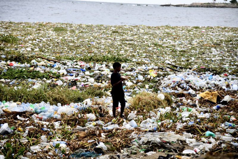 Un niño camina sobre un montón de basura y plásticos en la playa de Montesinos, en Santo Domingo.