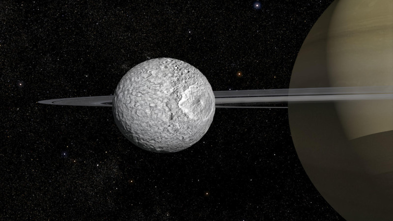 Representación de la luna Mimas con Saturno al fondo. Mimas es una de las lunas de Saturno y, como ya se sabe de otras, puede encerrar un océano bajo la superficie, el cual aún sería nuevo y estaría evolucionando, señala un nuevo estudio que ha analizado datos de la sonda Cassini.