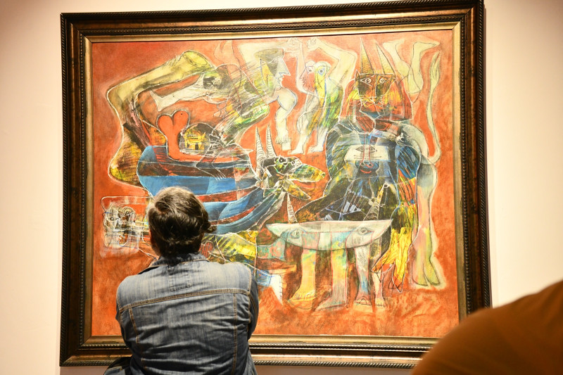 Un hombre observa una pintura de Ramón Oviedo.