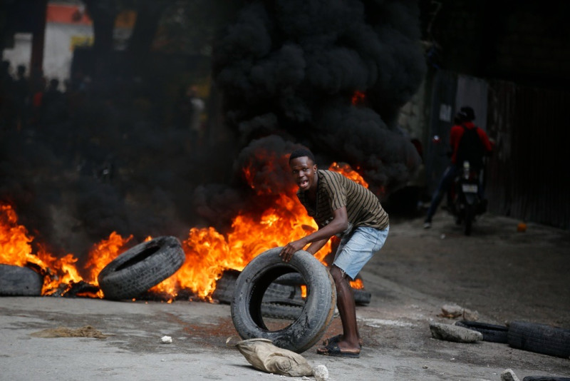 Un manifestante coloca neumáticos en una barricada en llamas durante una protesta para exigir la renuncia del primer ministro, Ariel Henry, en Puerto Príncipe, Haití, el 7 de febrero de 2024.
