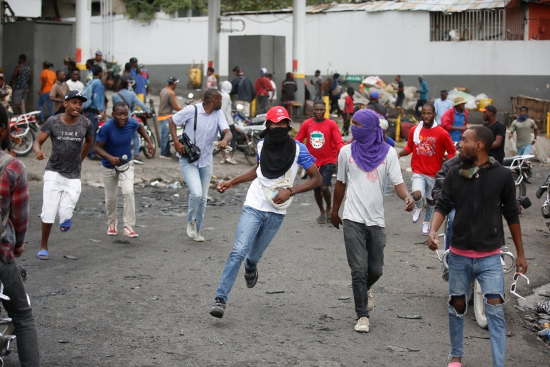 Los manifestantes corren en busca de refugio después de que la policía abriera fuego para dispersar a la multitud durante una manifestación que exigía la renuncia del primer ministro Ariel Henry.