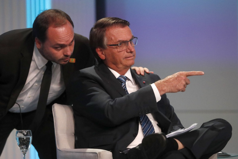 Carlos Bolsonaro, hijo del expresidente brasileño Jair Bolsonaro, susurra al oído a su padre en su llegada al debate presidencial en Río de Janeiro, el 29 de septiembre de 2022.