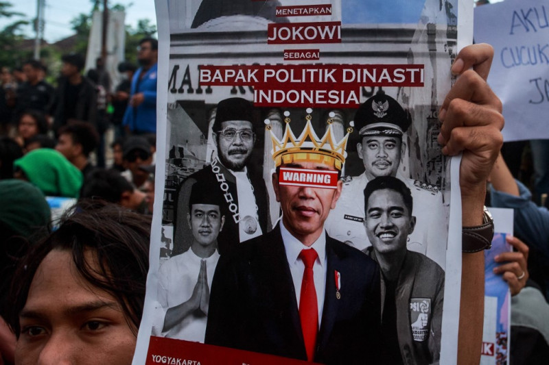 Un estudiante sostiene un cartel que muestra al presidente de Indonesia, Joko Widodo, y a sus familiares mientras cientos de estudiantes protestan contra la dinastía política de su familia en las elecciones de 2024 en Yogyakarta el 12 de febrero de 2024.