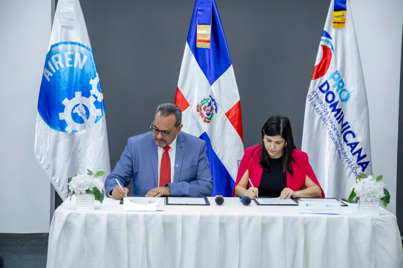 Biviana Riveiro Disla, directora de ProDominicana y Juan Bautista Ventura, presidente de la Junta Directiva de AIREN, mientras firman el acuerdo.