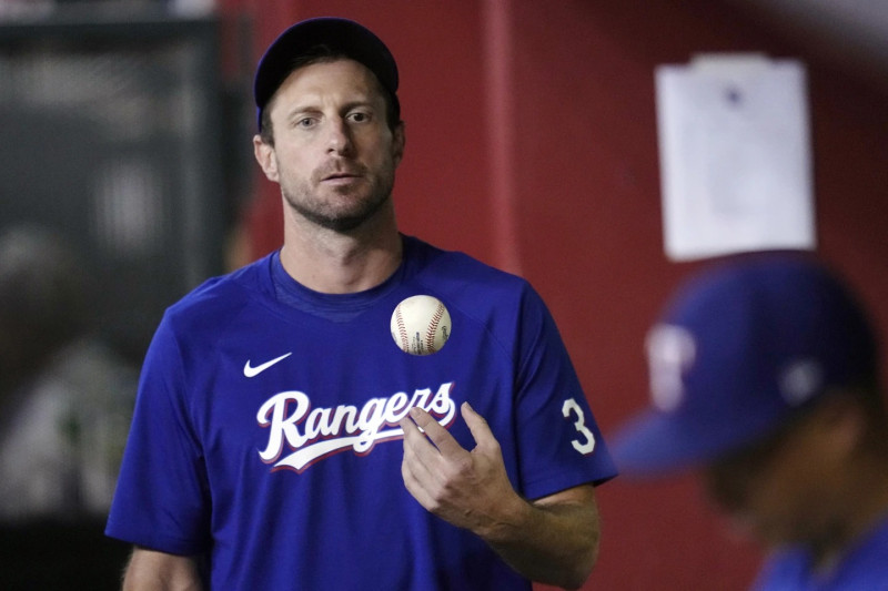 Max Scherzer, de los Texas Rangers, lanza la pelota en el aire mientras camina por el dugout.