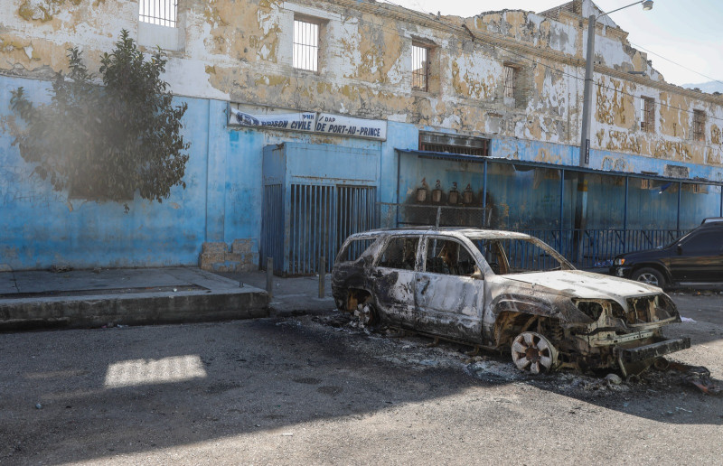 Se ve un automóvil quemado afuera de la Penitenciaría Nacional en el centro de Puerto Príncipe, Haití, el domingo 3 de marzo de 2024. Cientos de reclusos huyeron de la prisión principal de Haití después de que bandas armadas irrumpieran en las instalaciones durante la noche.
