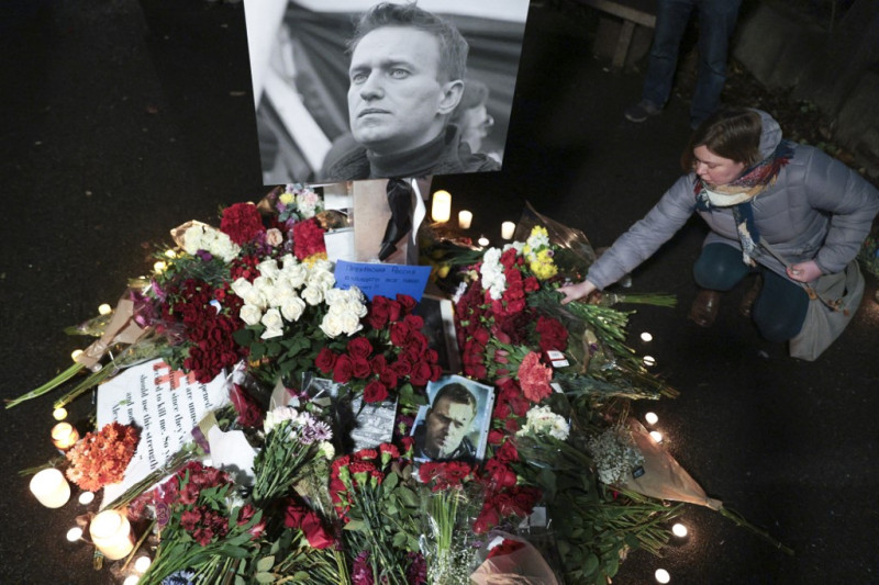 Varias personas dejan flores y velas durante un acto en memoria del fallecido líder opositor ruso Alexei NavalnI