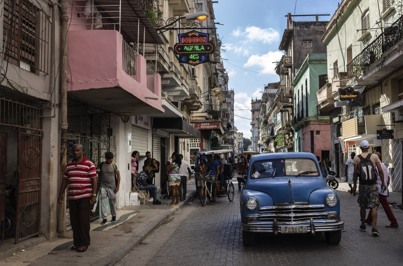 La gente camina bajo un cartel que anuncia una tienda de comestibles privada, a la izquierda, en La Habana, Cuba, el 11 de noviembre de 2023.