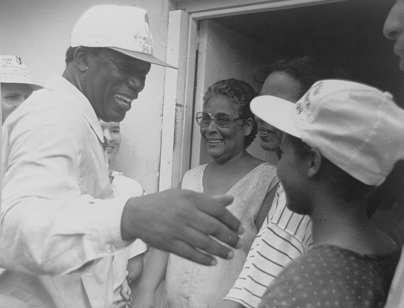 José Francisco Peña Gómez sonríe junto a niño y dos mujeres. Porta una gorra de color blanco con el logo del PRD.
