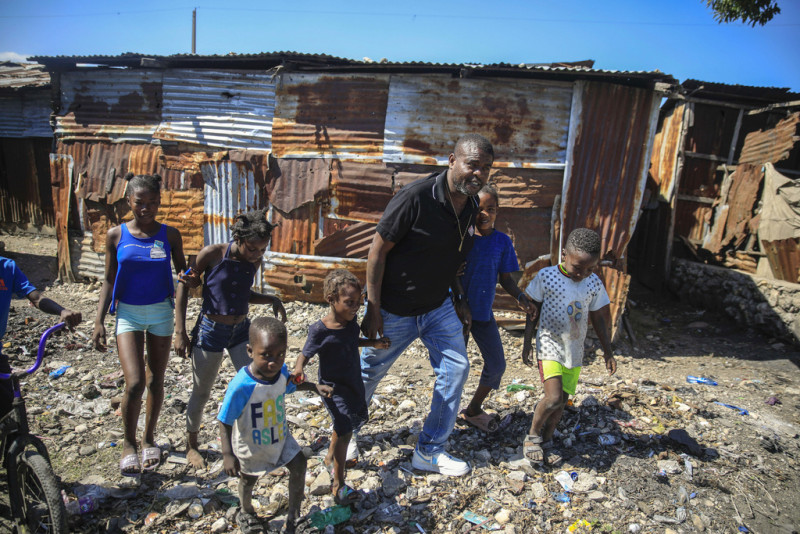 Jimmy Chérizier, un expolicía de élite conocido como Barbacue y que ahora dirige una federación de pandillas, camina de la mano de varios niños en una visita al distrito de La Saline en Puerto Príncipe, Haití, el 24 de enero de 2023.