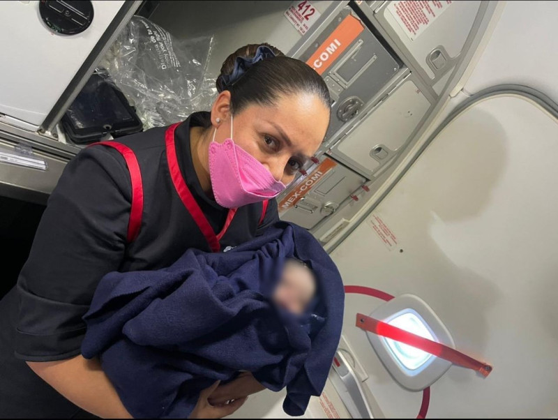 Asistente de vuelo de Aeroméxico con bebé recién nacido en brazos.