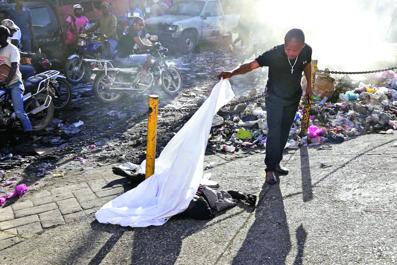 Una persona levanta la sábana que cubría un cadáver en el vecindario Petion Ville de Puerto Príncipe.