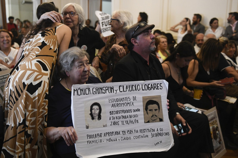 Personas sostienen fotografías de desaparecidos en un tribunal mientras escuchan el veredicto para expolicías y exmilitares  procesados ​​por crímenes de lesa humanidad durante la dictadura en La Plata, ayer.