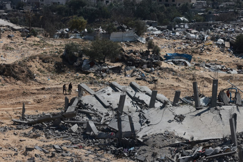 Varios hombres caminan en medio de la devastación causada por meses de bombardeos israelíes en Jan Yunis el 7 de abril de 2024, después de que Israel retirara sus fuerzas terrestres del sur de la Franja de Gaza