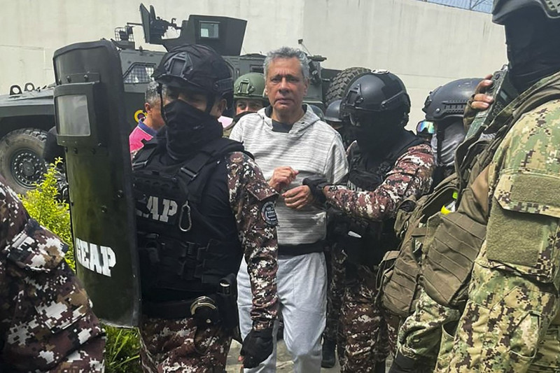 Esta foto difundida por la Policía ecuatoriana muestra a Jorge Glas escoltado por miembros del Grupo Especial de Acción Penitenciaria (GEAP) durante su llegada a la prisión de máxima seguridad La Roca en Guayaquil