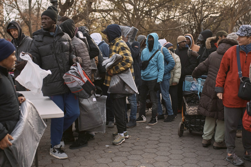 Migrantes toman mantas cerca de un Centro de Ayuda a Migrantes en la escuela primaria St. Brigid, el martes 5 de diciembre de 2023, en Nueva York.