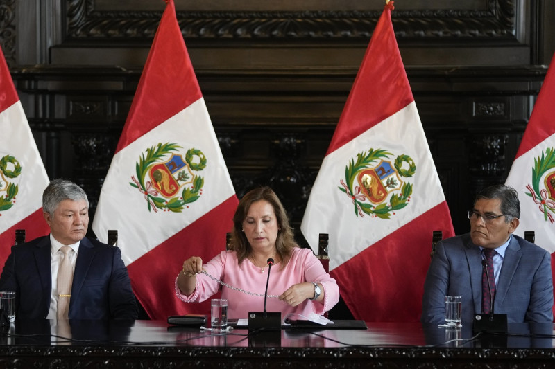 La presidenta de Perú, Dina Boluarte, muestra ayer un collar, acompañada por sus abogados Mateo Castañeda, a la izquierda, y Eduardo Barriga, en una conferencia de prensa en la Palacio de gobierno en Lima.