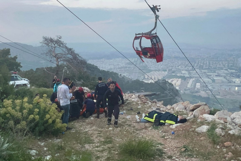 Esta fotografía tomada y publicada el 12 de abril de 2024 por la agencia de noticias turca DHA (Agencia de Noticias Demiroren) muestra a los equipos de rescate realizando una operación de rescate y ayudando a las personas heridas después de que la cabina de un teleférico se estrellara contra un poste de cable caído en el distrito de Konyaalti de Antalya.