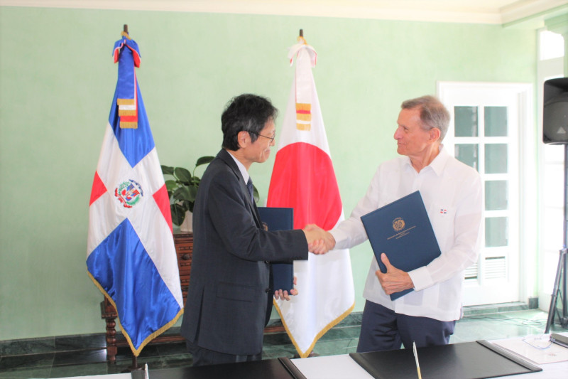 El embajador de Japón en el país, Masahiro Takagi, y el canciller dominicano Roberto Álvarez, hacen los saludos protocolares durante la firma.