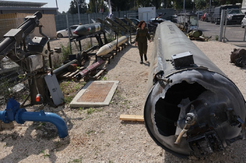 Un miembro del ejército israelí pasa junto a un misil balístico iraní, derecha, que cayó en Israel el fin de semana, durante una gira de prensa en la base militar de Julis, cerca de la ciudad de Kiryat Malachi, en el sur de Israel, el 16 de abril de 2024.