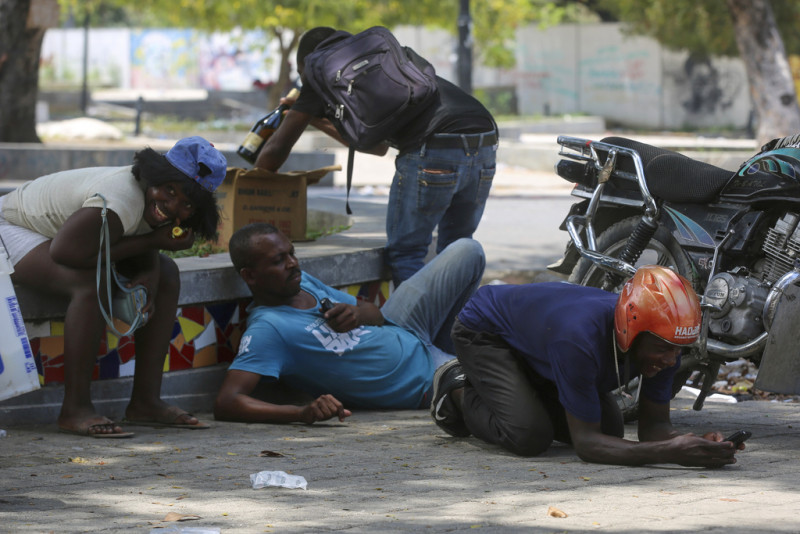 Varias personas se refugian de los disparos durante choques entre la policía y bandas armadas en las inmediaciones del Palacio Nacional, en Puerto Príncipe, Haití, el 8 de abril de 2024