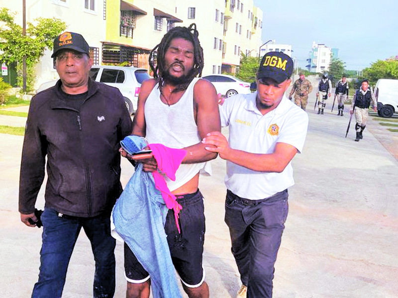 Oficiales de Migración conducen a un hombre que fue detenido durante una redada y que presumen es haitiano, para ser repatriado.