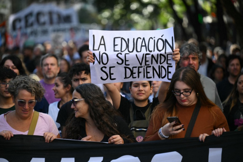 Un manifestante sostiene un cartel que dice "La educación no se vende, se defiende"