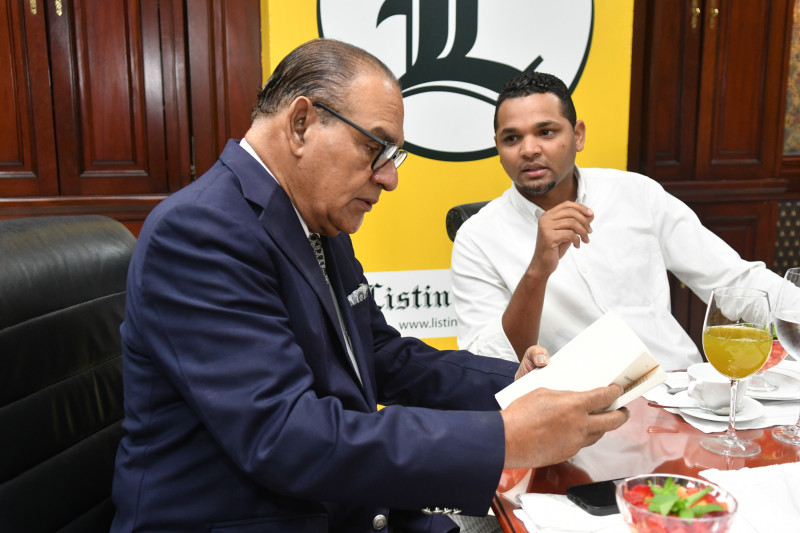 El director del Listín Diario, Miguel Franjul, hojea un libro de su autoría que le regaló el candidato vicepresidencial.