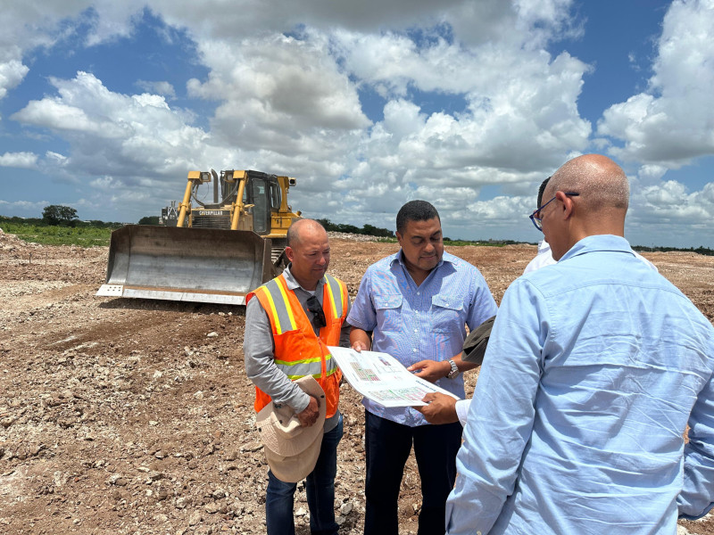 José P. Monegro, presidente del Comité Organizador de Santo Domingo 2026, escucha explicaciones de los encargados de los trabajos de movimiento de tierra.