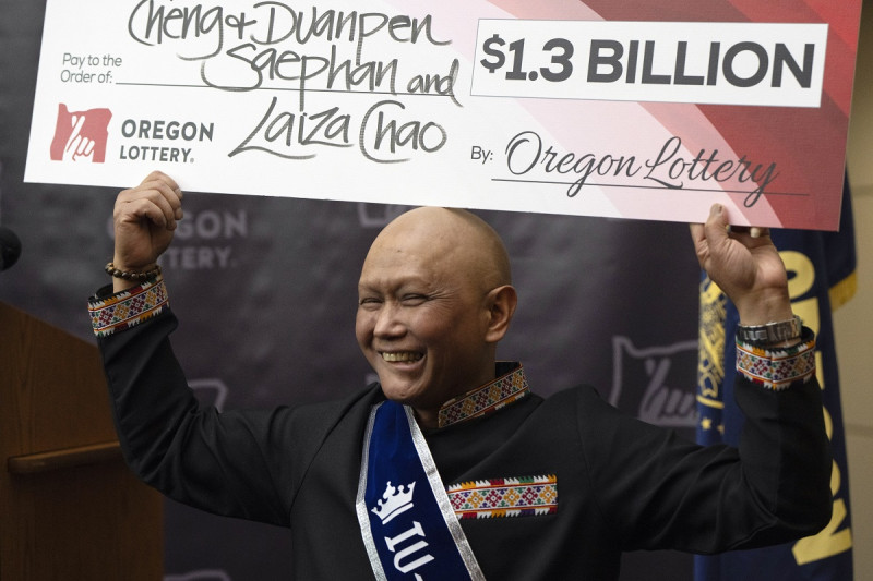 Cheng Saephan levanta un cheque después de hablar en una conferencia de prensa el lunes 29 de abril de 2024 en las oficinas de la Lotería de Oregon.