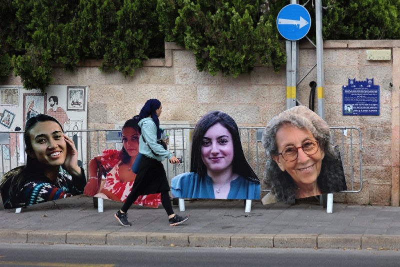 Una mujer pasa junto a retratos de mujeres israelíes retenidas como rehenes en Gaza desde los ataques del 7 de octubre de Hamás