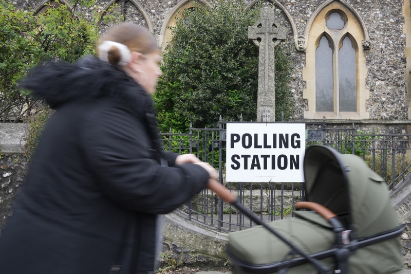 Una mujer llega con su bebé a un centro de votación en Londres, el jueves 2 de mayo de 2024.