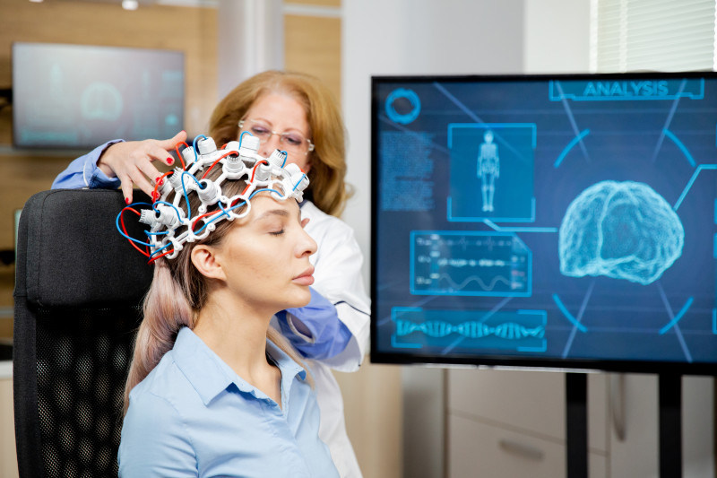 Médica coloca un casco de escaneo cerebral a paciente. Foto: DC Studio-Freepik.