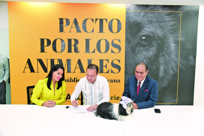 Abel Martínez, quien acudió con su mascota, firma el pacto junto a la presidenta de FEDDA, Lorenny Casado, y el director del Listín Diario, Miguel Franjul.